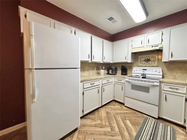 a kitchen with a refrigerator a sink and white cabinets