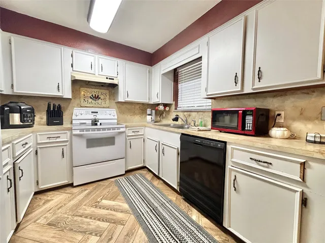 a kitchen with white cabinets sink and appliances