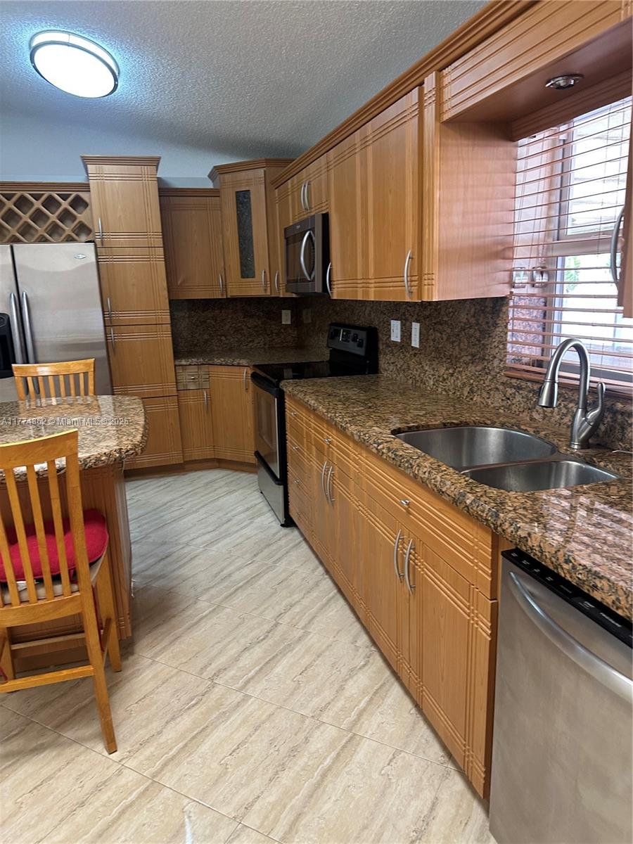 Westbrooke at Avalon Hialeah, FL 33015 - Photo 4 of 24 a kitchen with stainless steel appliances granite countertop a sink wooden cabinets and granite counter tops