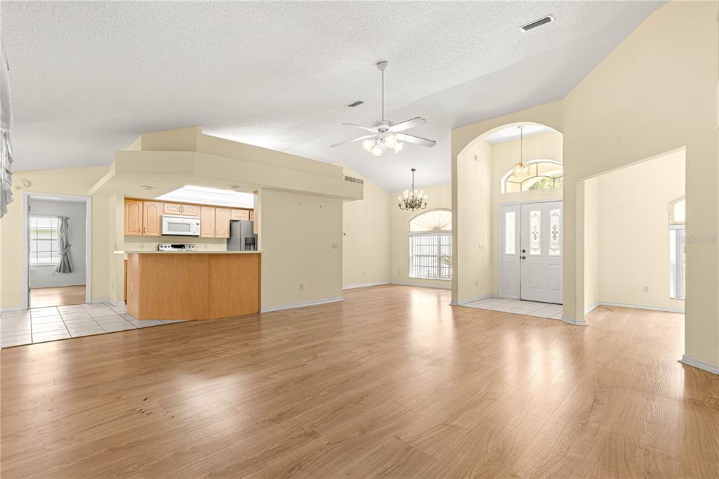 10884 Southwest 53rd Circle Ocala, FL 34476 - Photo 11 of 57 an empty room with wooden floor and kitchen view