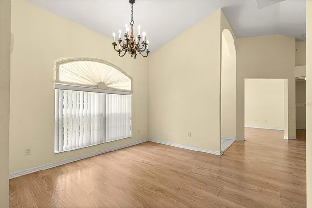 an empty room with wooden floor chandelier and entryway