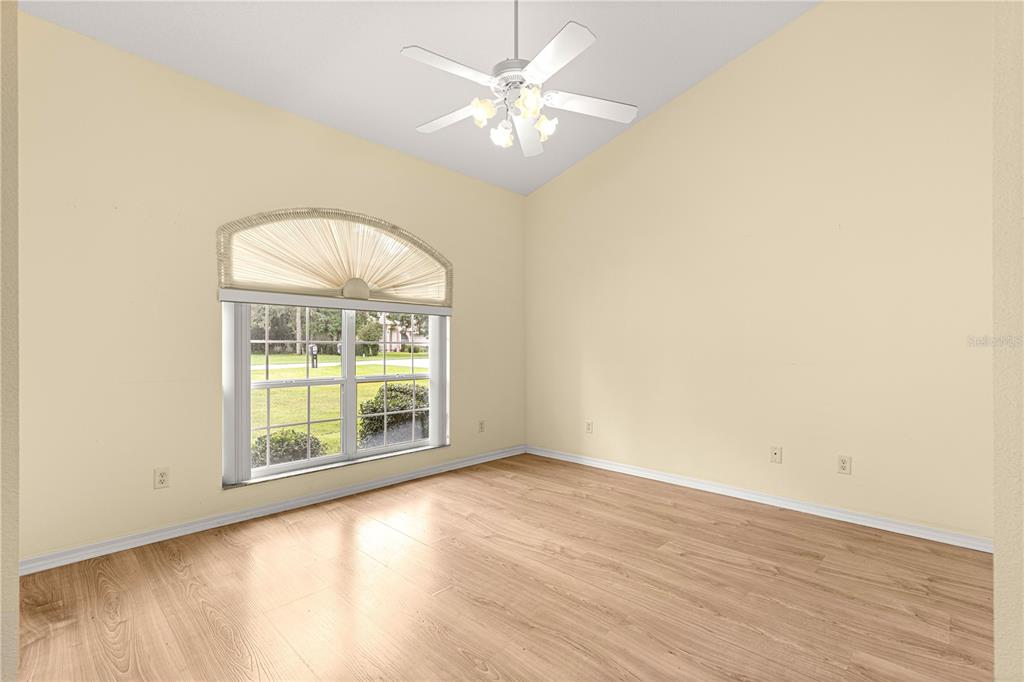 10884 Southwest 53rd Circle Ocala, FL 34476 - Photo 6 of 57 an empty room with wooden floor chandelier fan and windows