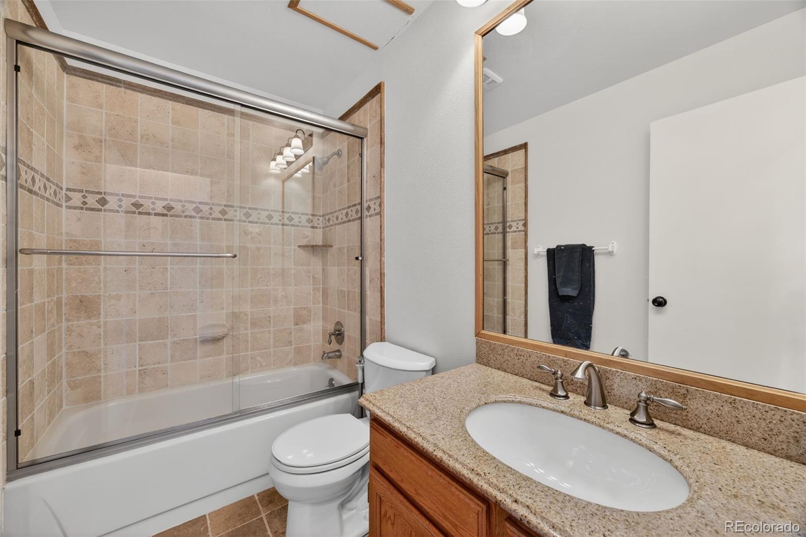 8764 Wildrose Court Highlands Ranch, CO 80126 - Photo 12 of 50 a bathroom with a granite countertop sink toilet mirror and shower
