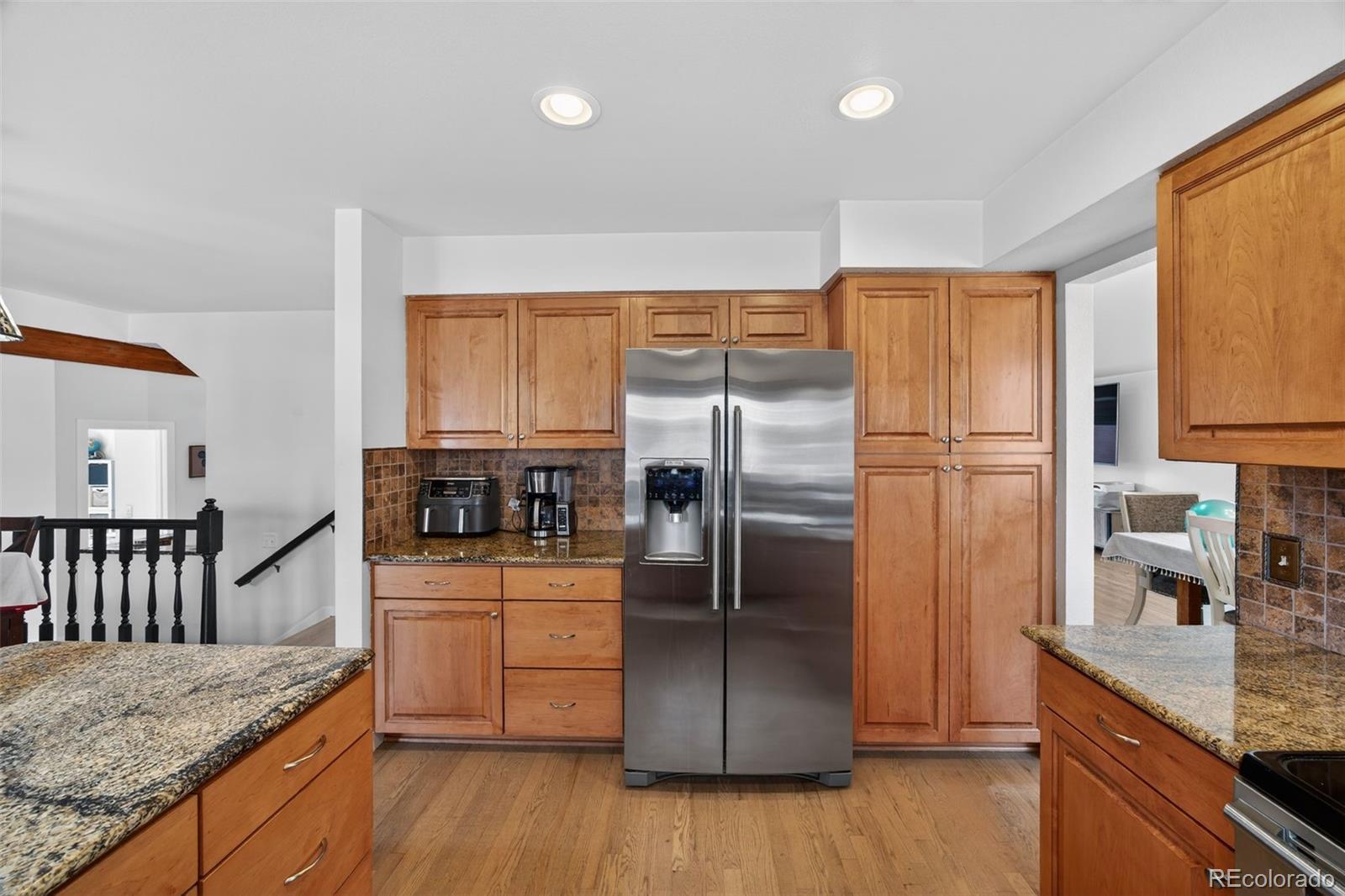 8764 Wildrose Court Highlands Ranch, CO 80126 - Photo 17 of 50 a kitchen with granite countertop a refrigerator a sink a stove and wooden floor
