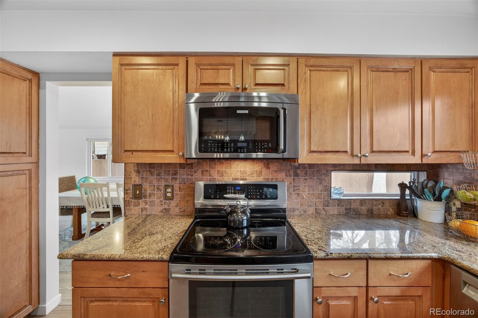 8764 Wildrose Court Highlands Ranch, CO 80126 - Photo 19 of 50 a kitchen with granite countertop a stove sink and cabinets