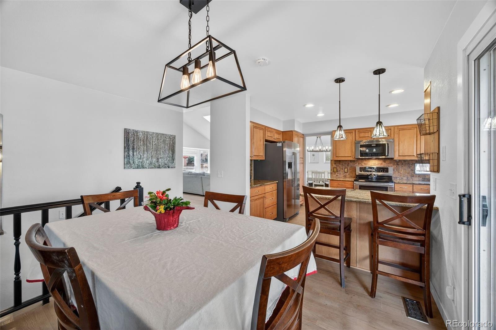 8764 Wildrose Court Highlands Ranch, CO 80126 - Photo 25 of 50 a kitchen with stainless steel appliances a dining table chairs and a refrigerator