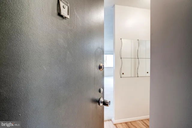 a view of a hallway with wooden floor and a bathroom