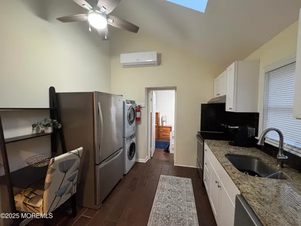 a kitchen with granite countertop stainless steel appliances a sink dishwasher a refrigerator a stove and a sink with wooden floor