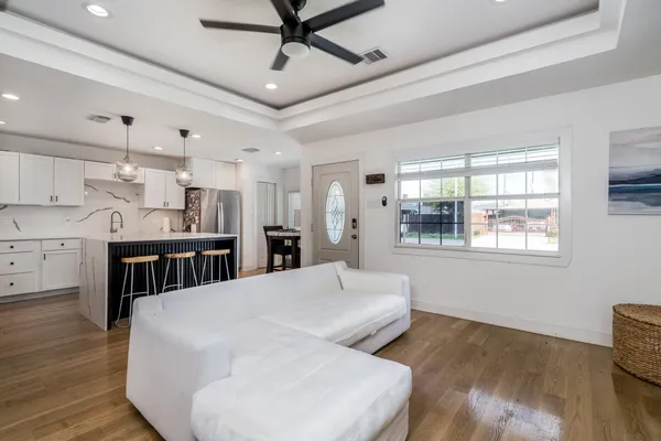 a large white kitchen with a large window stainless steel appliances and wooden floor