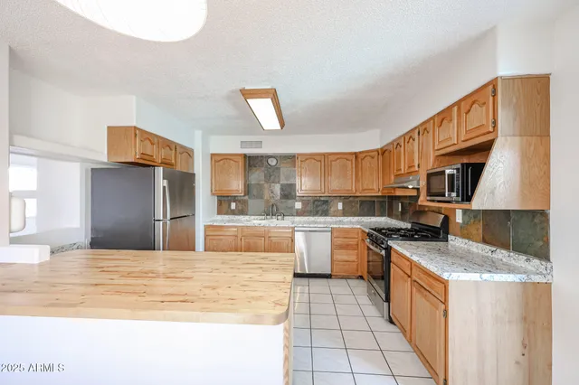 a kitchen with stainless steel appliances granite countertop a stove a sink and a microwave