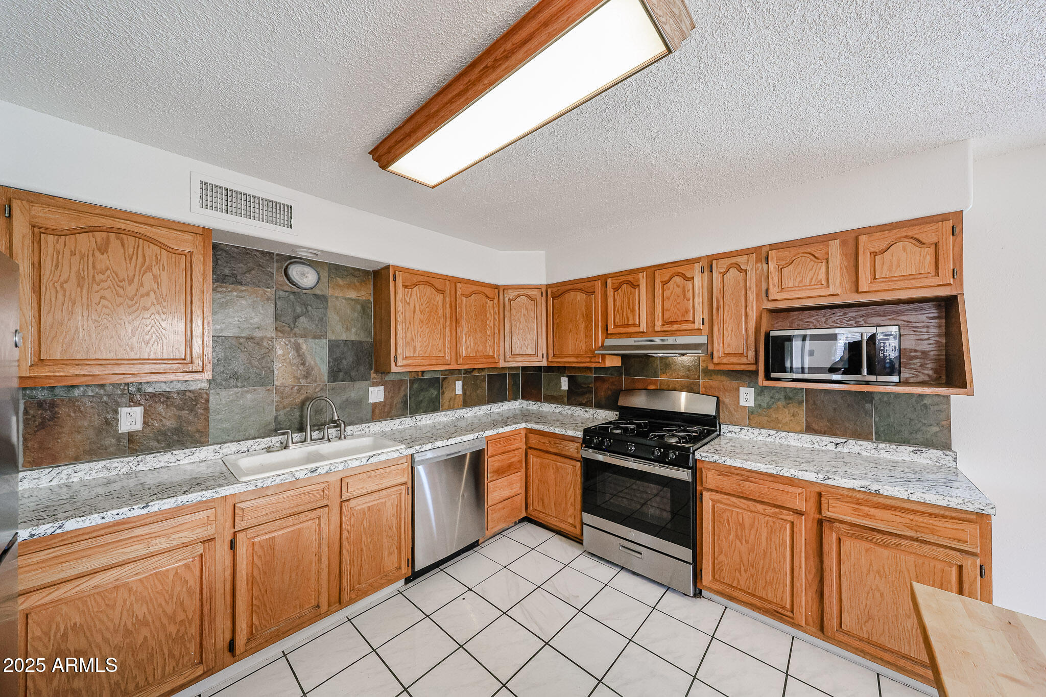 3408 West Port Au Prince Lane Phoenix, AZ 85053 - Photo 30 of 61 a kitchen with stainless steel appliances granite countertop a stove sink and cabinets