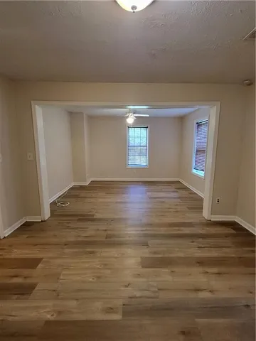 a view of an empty room with window and wooden floor