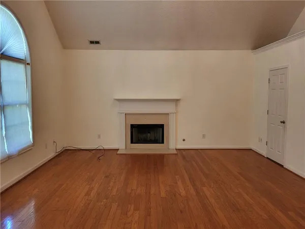 a view of an empty room with wooden floor and a fireplace