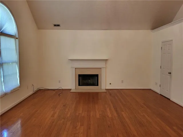 a view of an empty room with wooden floor and a fireplace