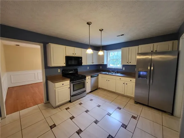 a kitchen with granite countertop a refrigerator oven a sink dishwasher and a refrigerator
