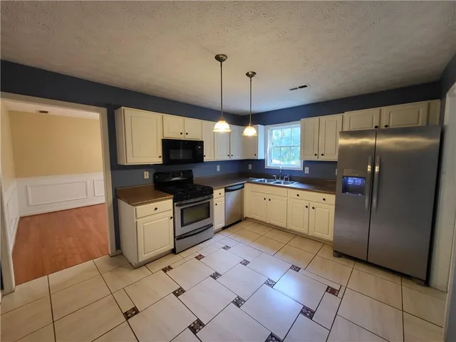 a kitchen with granite countertop a refrigerator oven a sink dishwasher and a refrigerator