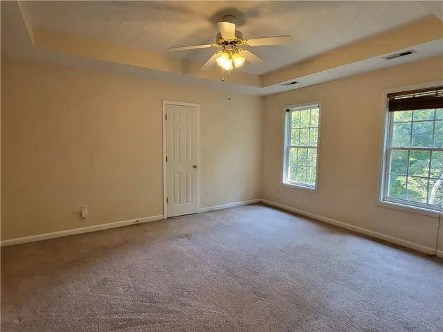 an empty room with windows and chandelier fan