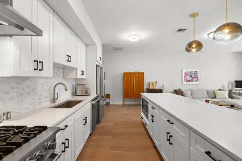a kitchen with granite countertop a sink a stove and a wooden floors