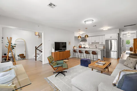 a living room with furniture kitchen view and a chandelier