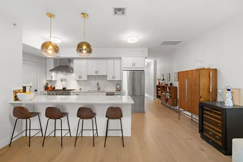 a kitchen with stainless steel appliances granite countertop a sink a stove a refrigerator and island with wooden floor