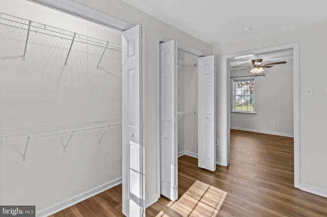 a view of empty room with wooden floor and fan