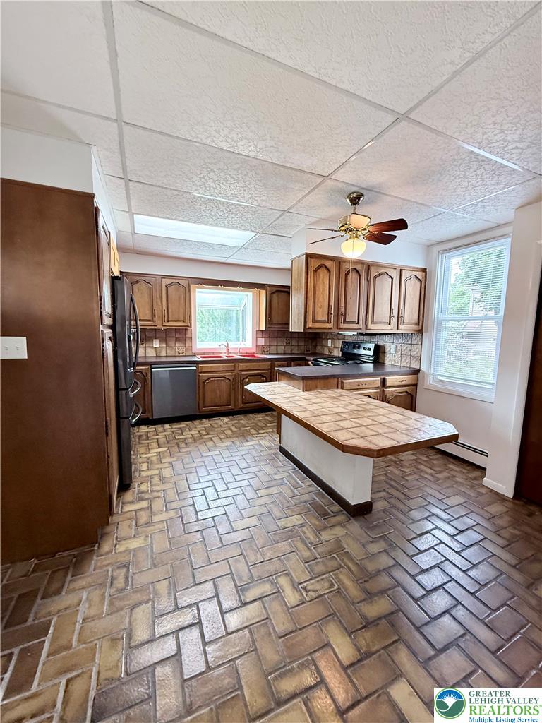 5540 Main Street Whitehall, PA 18052 - Photo 9 of 53 Herringbone-patterned floors anchor this well-appointed kitchen, featuring a central island and warm wood cabinetry.