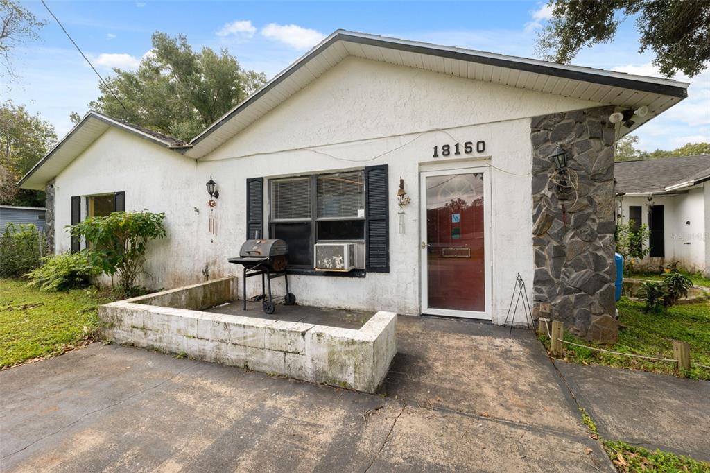 18160 Spangler Avenue Brooksville, FL 34604 - Photo 18 of 37 a view of a white house with a large windows and flower plants