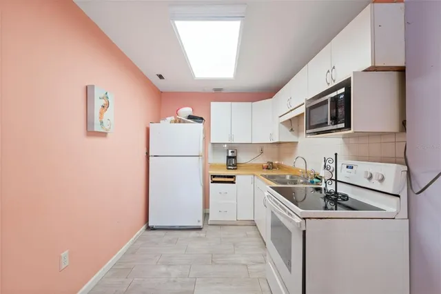 a kitchen with a sink a refrigerator a microwave and cabinets