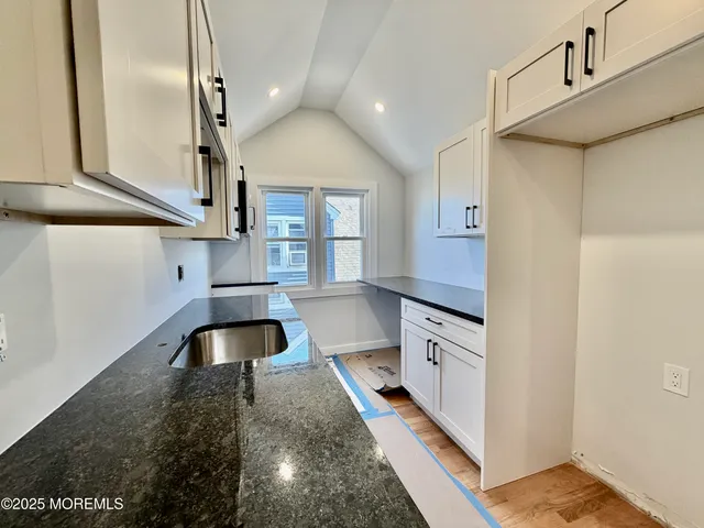 a hall with stainless steel appliances granite countertop a sink and a stove top oven