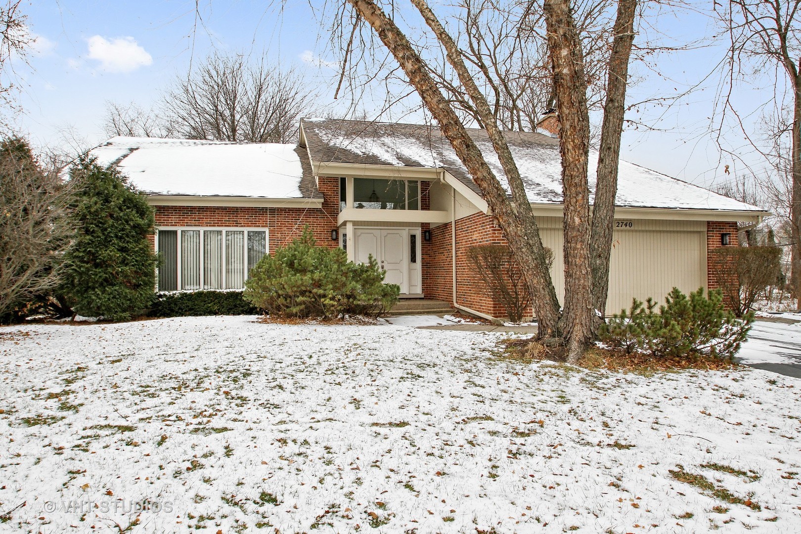 a front view of a house with a yard and trees