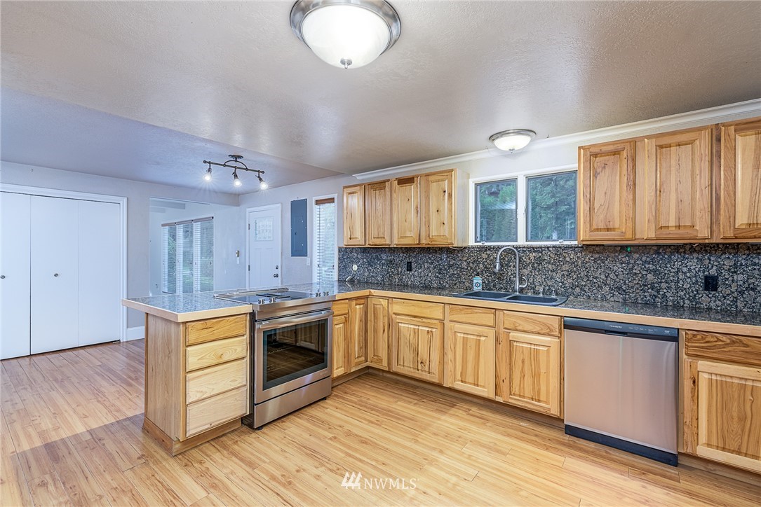7586 Goodwin Road Everson, WA 98247 - Photo 9 of 22 a kitchen with stainless steel appliances granite countertop a stove a sink dishwasher and a microwave oven with wooden floor