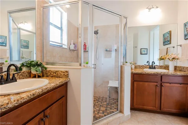 a bathroom with a granite countertop sink a mirror and a shower