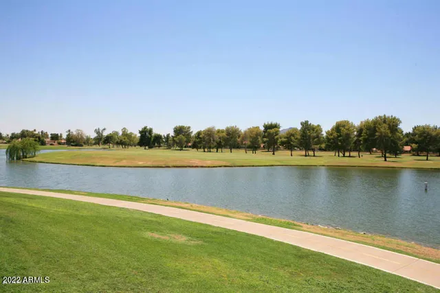 a view of a swimming pool with lake and houses in the back