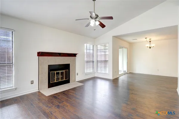 an empty room with wooden floor fireplace and windows