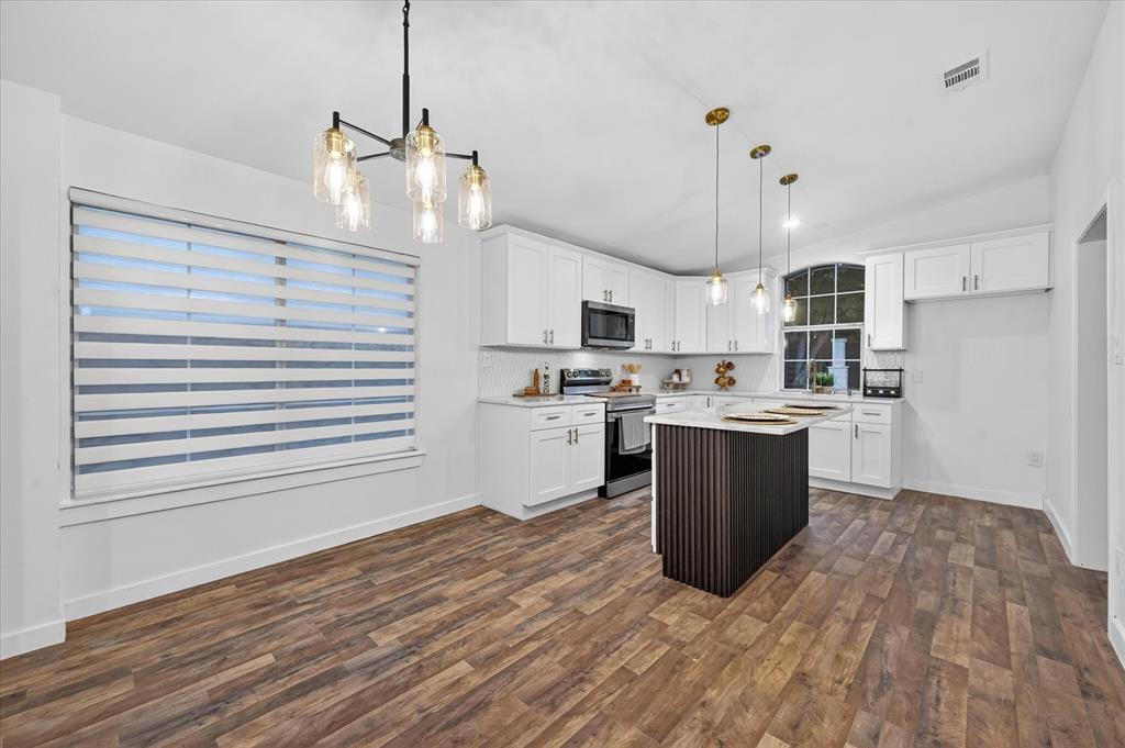 538 Pemberton Hill Road Dallas, TX 75217 - Photo 22 of 31 Open-concept kitchen featuring white cabinetry, a dark wood-finish island with a light countertop, and wood-finish flooring
