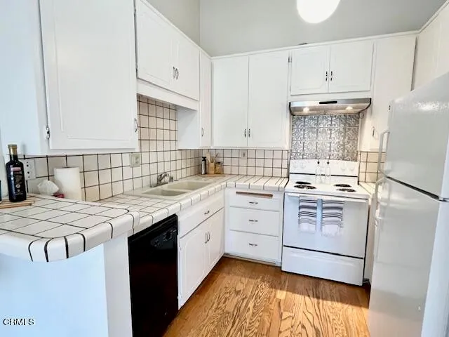 a kitchen with stainless steel appliances kitchen island granite countertop a refrigerator a stove a sink and a dining table with wooden floor