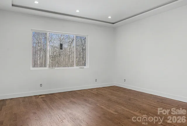 an empty room with wooden floor and window