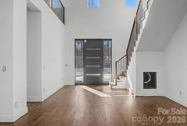 a view of an empty room with wooden floor and stairs