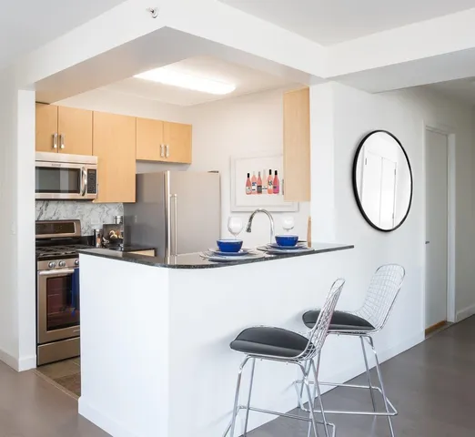 a kitchen with stainless steel appliances granite countertop a stove top oven a sink a dining table and chairs with wooden floor