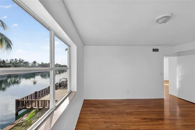 a view of an empty room with wooden floor and windows