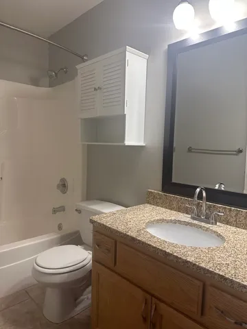 a bathroom with a granite countertop sink a toilet and a mirror