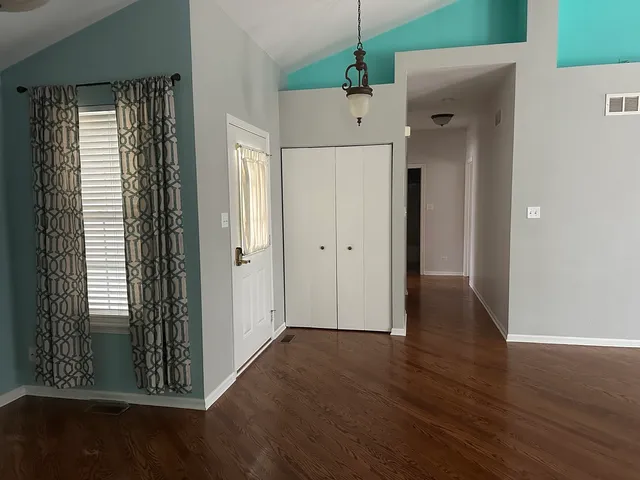 an empty room with wooden floor closet and windows