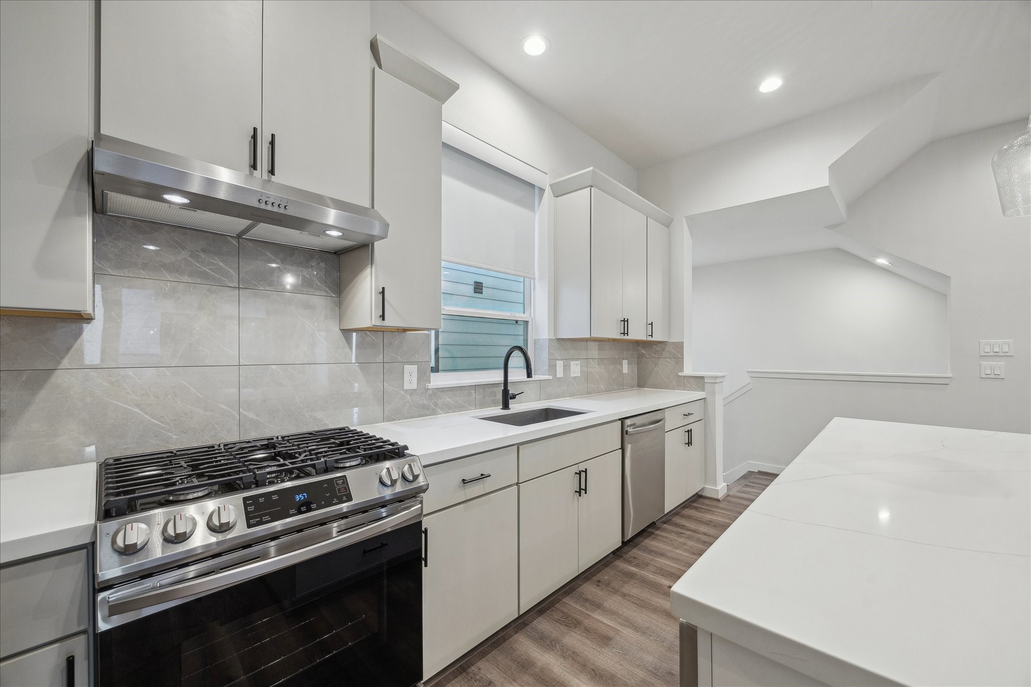1603 Patterson Street, Unit E Houston, TX 77007 - Photo 12 of 32 This kitchen features sleek modern cabinetry, stainless steel appliances, and a stylish backsplash. The spacious layout includes a large countertop area, perfect for cooking and entertaining. The neutral color palette and ample lighting create a bright, inviting atmosphere.