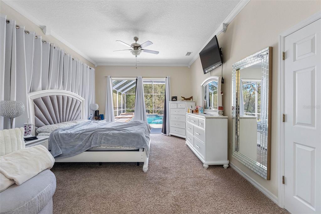 9336 Tooke Shore Drive Weeki Wachee, FL 34613 - Photo 14 of 44 a spacious bedroom with a bed and a chandelier