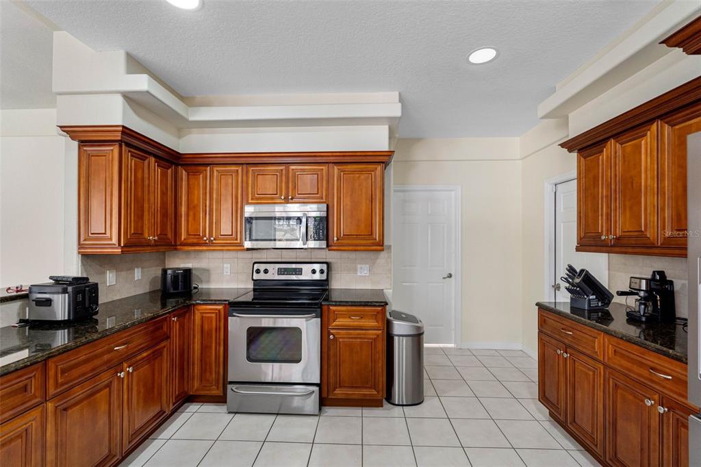9336 Tooke Shore Drive Weeki Wachee, FL 34613 - Photo 7 of 44 a kitchen with stainless steel appliances granite countertop a stove a sink dishwasher and a refrigerator