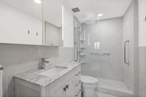 a bathroom with a granite countertop sink a toilet and shower