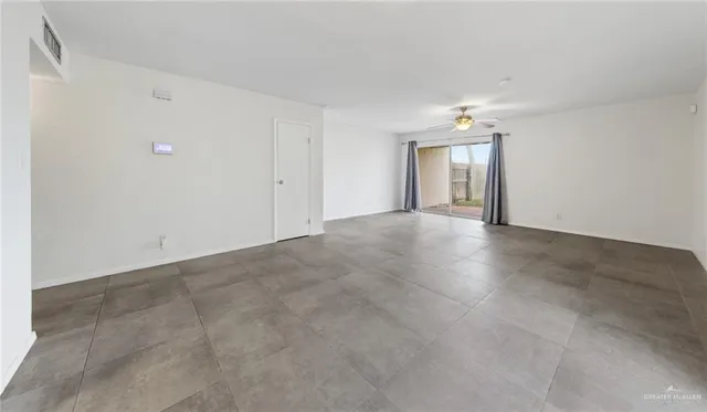 an empty room with a chandelier fan and windows