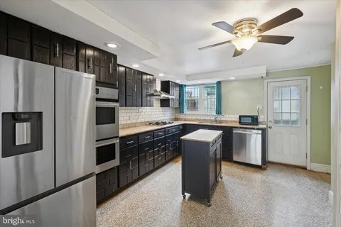 a kitchen with stainless steel appliances granite countertop a refrigerator a sink dishwasher a stove with white cabinets and wooden floor