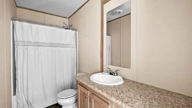 a bathroom with a granite countertop sink toilet and a mirror
