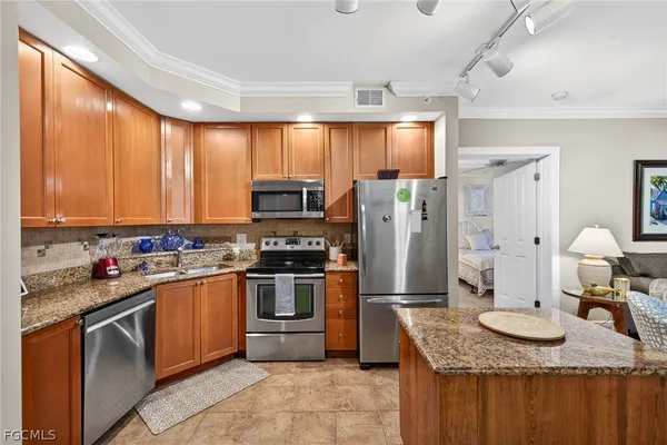 a kitchen with granite countertop stainless steel appliances a stove sink and refrigerator